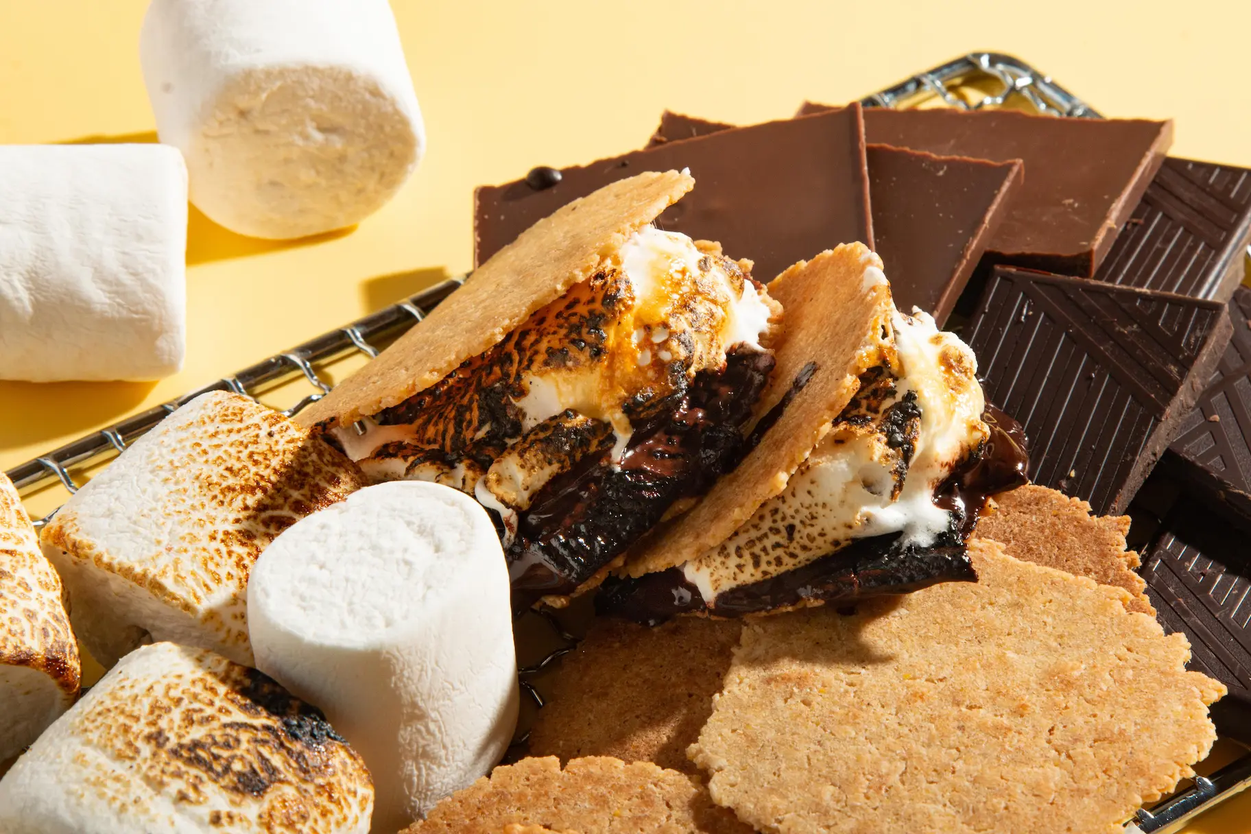 S’mores with toasted marshmallows and melted chocolate on graham crackers, with chocolate bars.