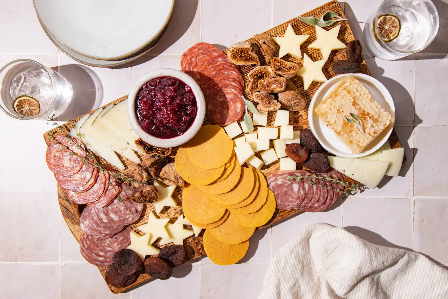 Charcuterie board with crackers, cheeses, salami, figs and cranberry dip bowl.