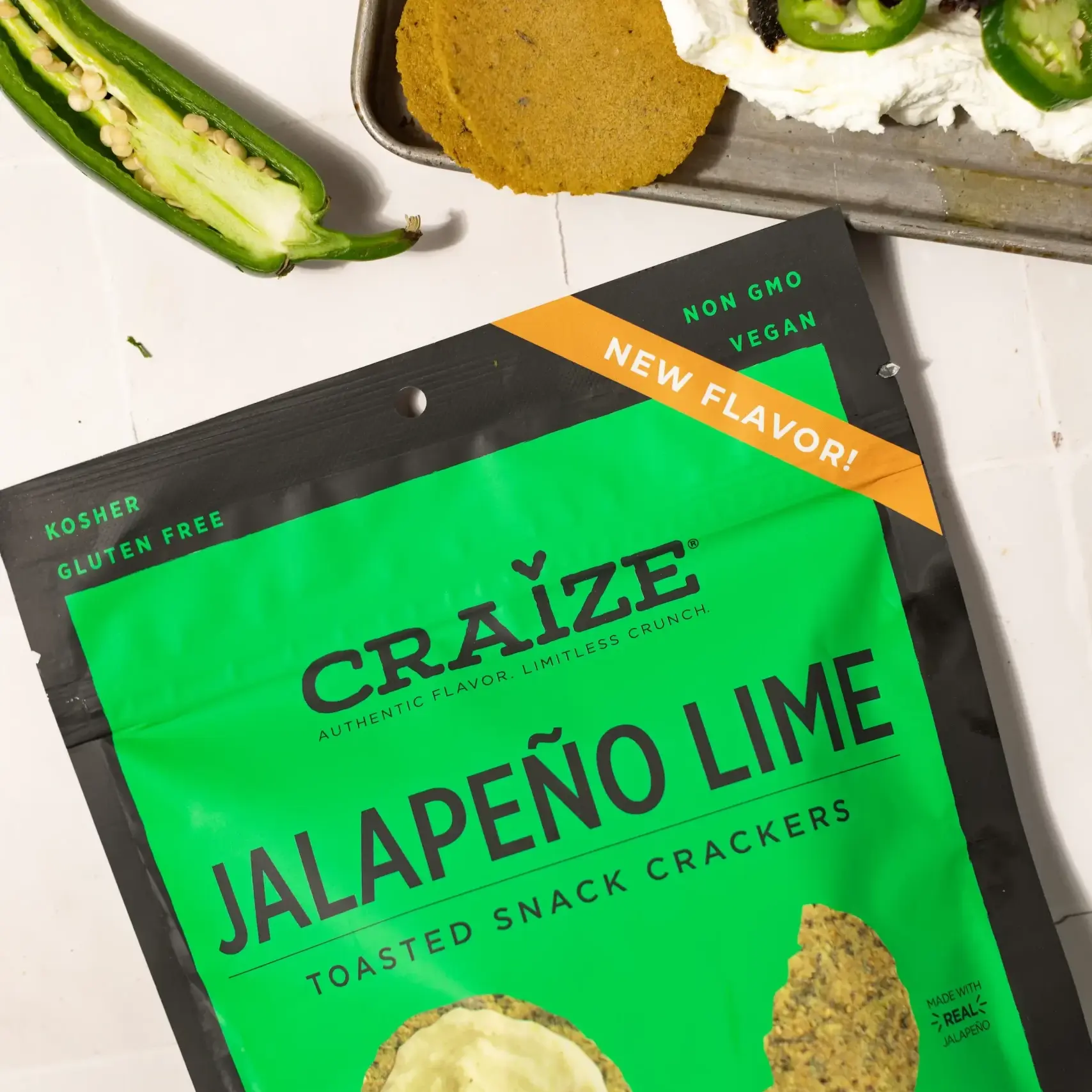 Craize Jalapeño Lime crackers bag beside dip topped with meat and sliced jalapeños.